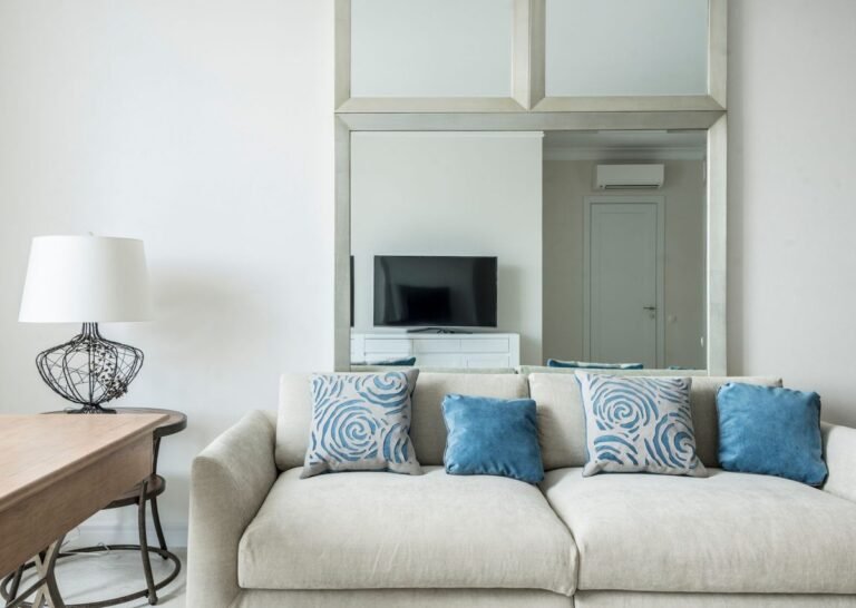 Bright and cozy small living room decor with a light sofa, round coffee table, and a large mirror