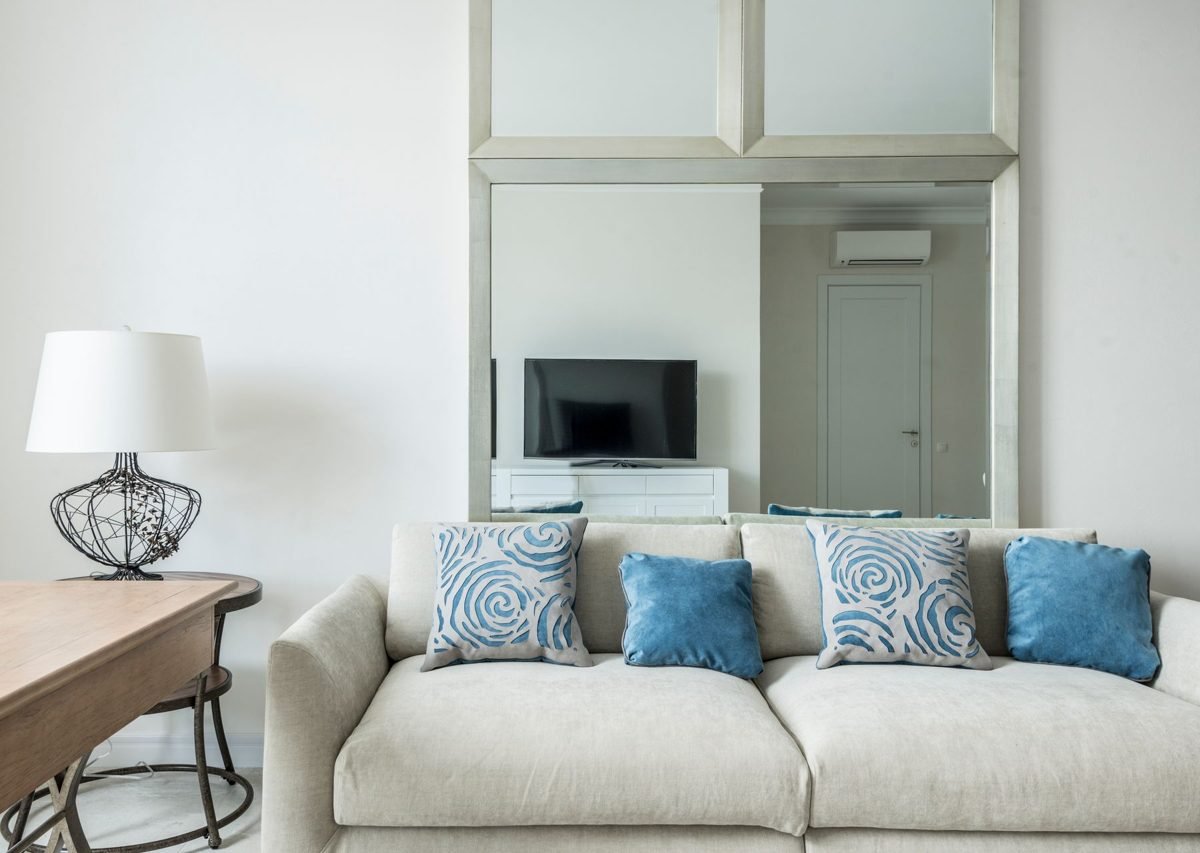 Bright and cozy small living room decor with a light sofa, round coffee table, and a large mirror