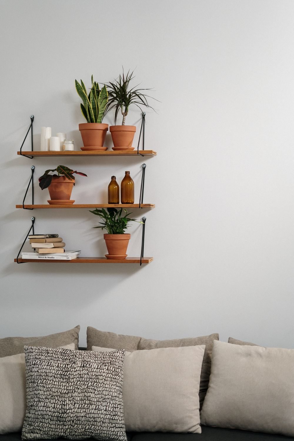 Tall floating shelves using vertical wall space above a sofa in a small living room