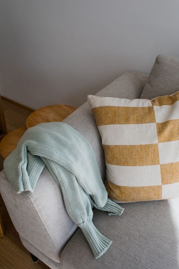 Neutral small living room with knit throws, linen pillows, and wood textures for a cozy feel