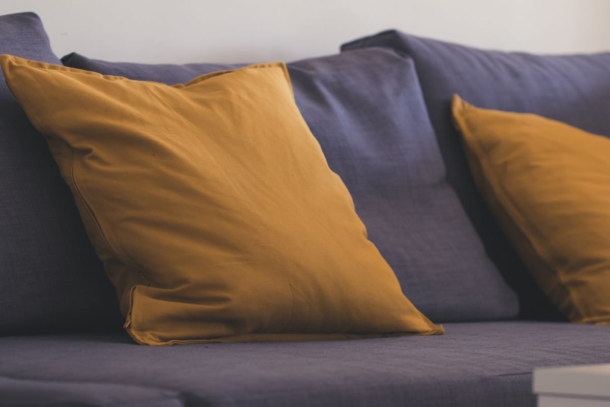 Budget small living room refresh with a thrift mirror, light rug, and new pillows on a sofa